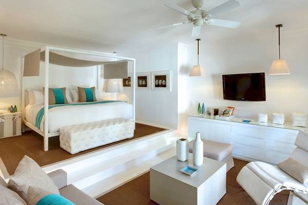 Schlafzimmer im LUX Belle Mare Resort & Villas mit einem vierposterbett, weichen kissen und einem weissen kleiderschrank.