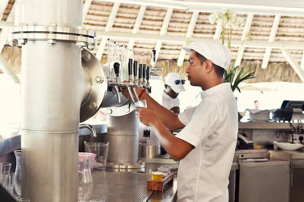 Mitarbeiter im LUX Belle Mare Resort & Villas zapft Bier aus einem Zapfhahn.