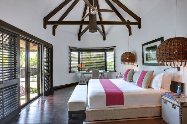 Schlafzimmer im LUX Belle Mare Resort & Villas mit einem großen Bett, Nachttischen und Lampen.