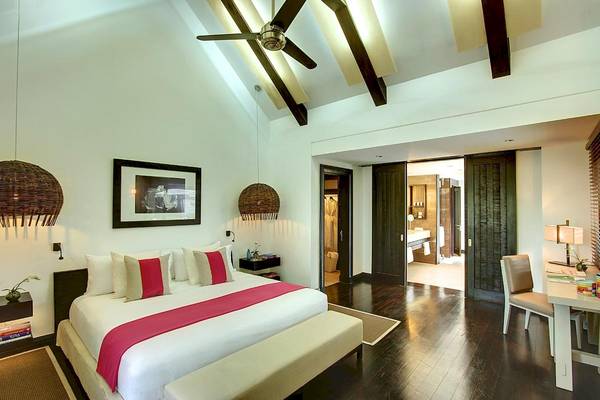 Luxuriöses Schlafzimmer im LUX Belle Mare Resort & Villas mit einem großen Bett, Kissen, Decken, Nachttischen, einer Lampe und einem offenen Badezimmer.