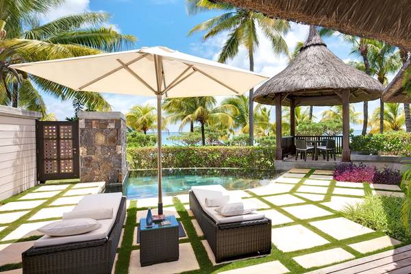 Luxuriöser Poolbereich im Belle Mare Resort mit Loungestühlen und Sonnenschirm.