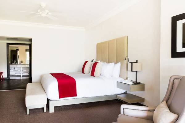 Schlafzimmer im LUX Belle Mare Resort & Villas mit einem großen Bett, Nachttischen und einem Stuhl.