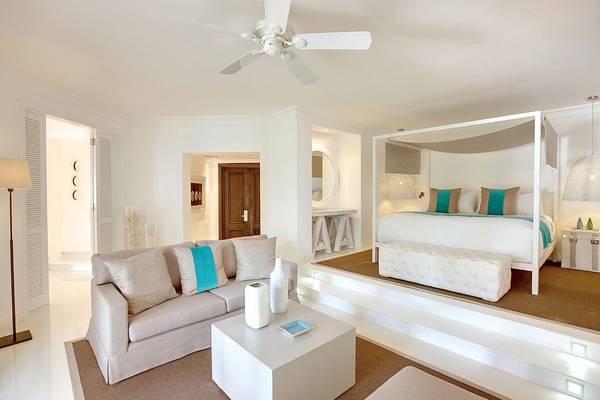 Innenansicht des Schlafzimmers im LUX Belle Mare Resort & Villas mit Bett, Couch und Tisch.