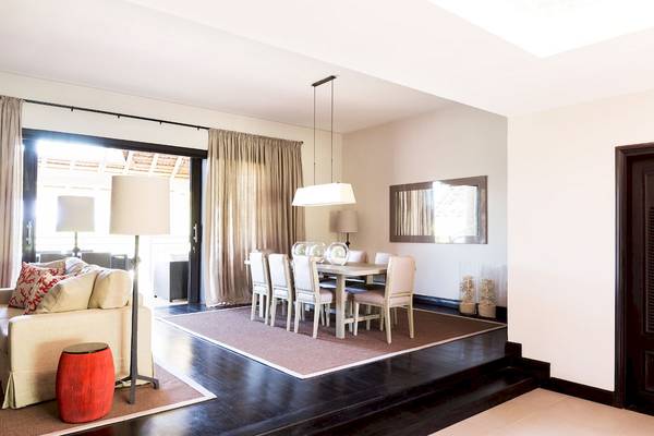 Wohnzimmer im LUX Belle Mare Resort & Villas mit Esstisch, Stühlen, Teppich, Lampe und Sofa.
