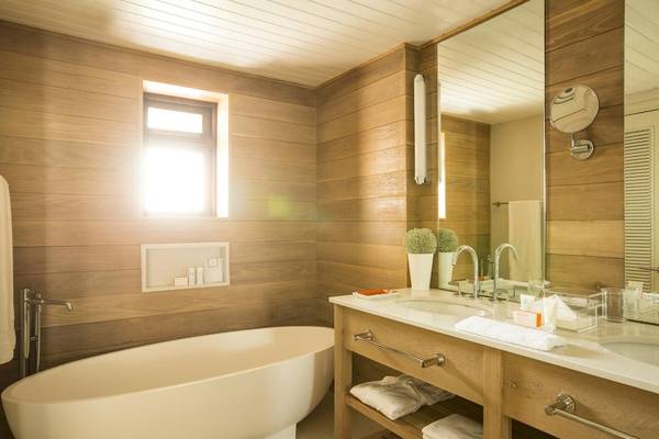 Badezimmer im LUX Belle Mare Resort & Villas mit Badewanne, Waschbecken und Spiegeln.