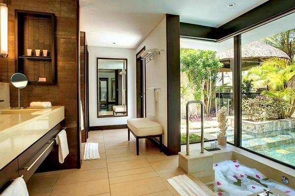 Badezimmer im LUX Belle Mare Resort & Villas mit Badewanne, Spiegel und Blick auf einen Pool.
