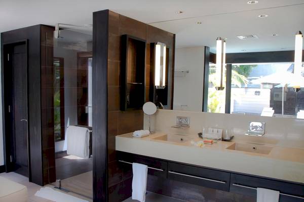 Badezimmer des LUX Belle Mare Resort & Villas mit spiegelverkleideter Wand und Doppelwaschbecken.