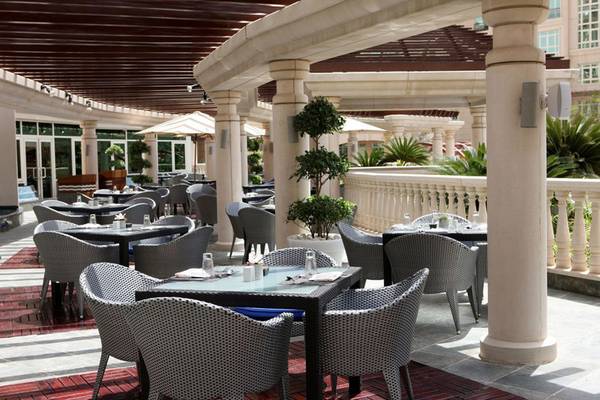 Terrasse des Swissotel Al Murooj Dubai Hotels mit Tischen und Stühlen unter einem Pavillon.