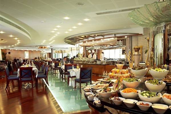 Innenansicht des Restaurants im Swissotel Al Murooj Dubai mit gedeckten Tischen und Buffet.
