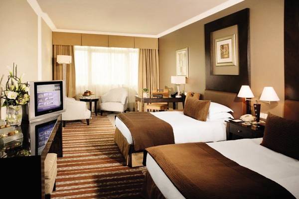 Doppelzimmer im Swissotel Al Murooj Dubai mit Fernseher, Schreibtisch und Sesseln.