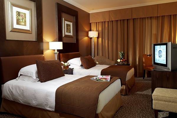 Hotelzimmer mit zwei Betten, brauner Dekor und Fernseher.