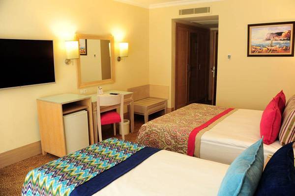 Doppelzimmer im Orange County Belek - Family Concept Hotel mit zwei Betten, Schreibtisch, Fernseher und Spiegel.