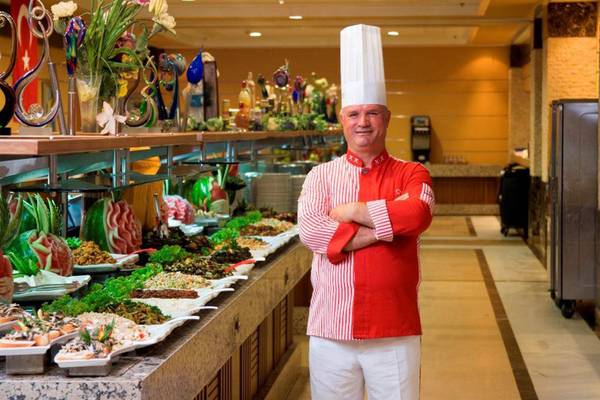 Ein Koch im Orange County Belek - Family Concept Hotel steht vor einem Buffet.