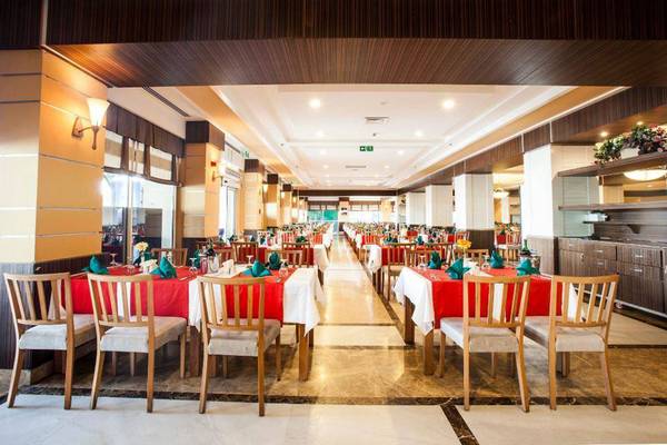 Innenansicht des Restaurants im Orange County Belek - Family Concept Hotel mit gedeckten Tischen und Stühlen.