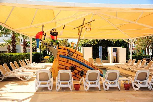 Poolbereich im Orange County Belek Hotel mit Piratenschiff Dekoration und Sonnenliegen.