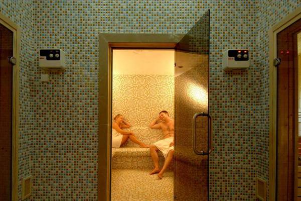 Sauna im Orange County Belek - Family Concept Hotel mit zwei Personen und einer Frau, die beobachtet