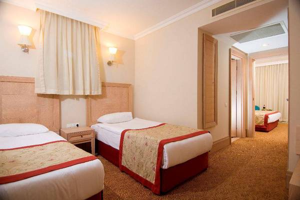 Doppelzimmer im Orange County Belek - Family Concept Hotel mit zwei Betten, Nachttischen und Wandlampen.