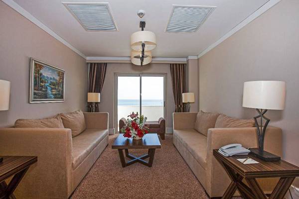 Hotelzimmer mit Meerblick, zwei Sofas, Tisch, Blumen, Telefon und Lampen.
