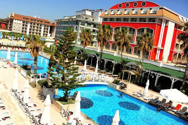 Familienkonzept-Hotel Orange County Belek mit Poolbereich und Sonnenliegen.
