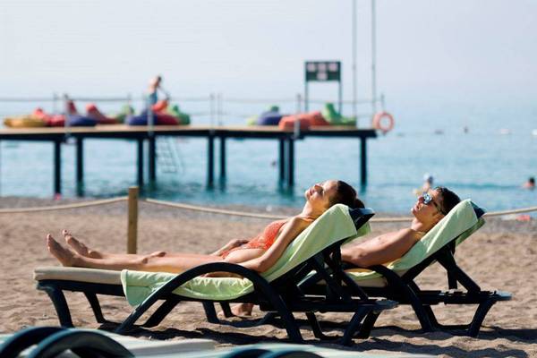 Gäste am Strand des Orange County Belek - Family Concept Hotels, die sich entspannen.