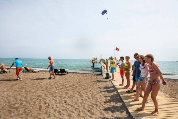 Strandszene mit Hotelgästen und Wassersport auf der Orange County Belek Family Concept