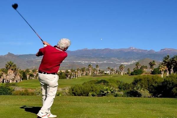 Golfspieler schlägt auf einem Golfplatz mit Bergen im Hintergrund