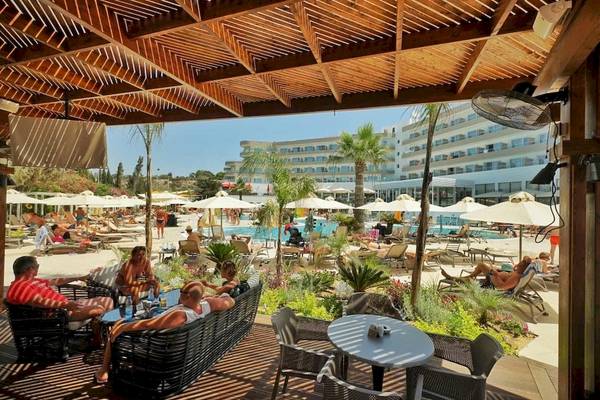 Gäste entspannen auf der Terrasse des Melissi Beach Hotel & Spa mit Blick auf den Pool.