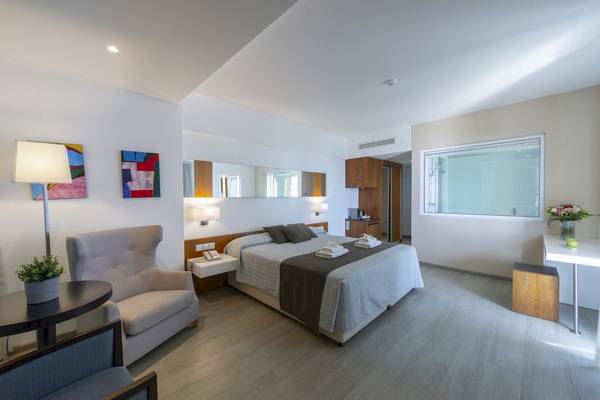 Elegantes Zimmer im Melissi Beach Hotel & Spa mit Doppelbett, Lampen und Gemälden an der Wand.