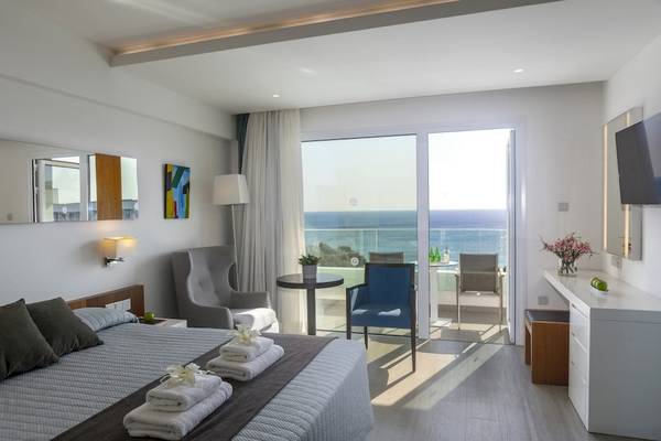 Hotelzimmer mit Meerblick, Bett, Sesseln, Tisch, Fernseher und Balkon