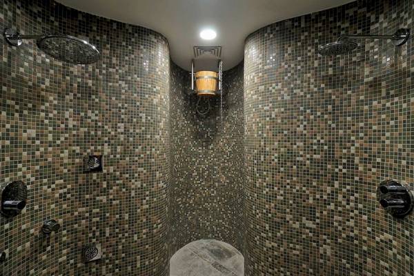 Eine geflieste Dusche im Melissi Beach Hotel & Spa mit zwei Duschköpfen und einer Holzeimer.