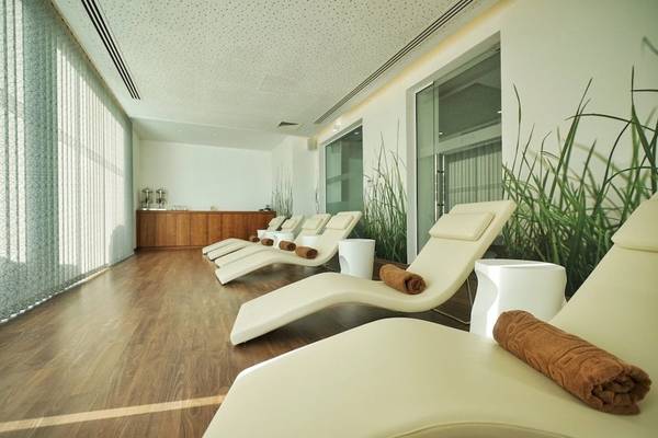 Loungebereich im Melissi Beach Hotel & Spa mit weißen Liegen und Holzböden.