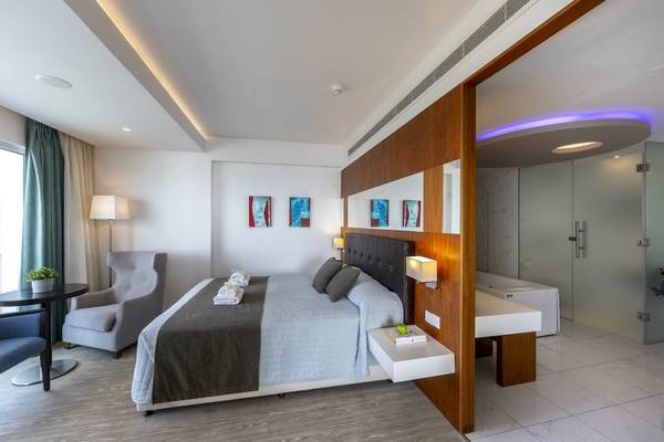 Modernes Hotelzimmer im Melissi Beach Hotel & Spa mit Bett, Tisch, Stuhl und Bad