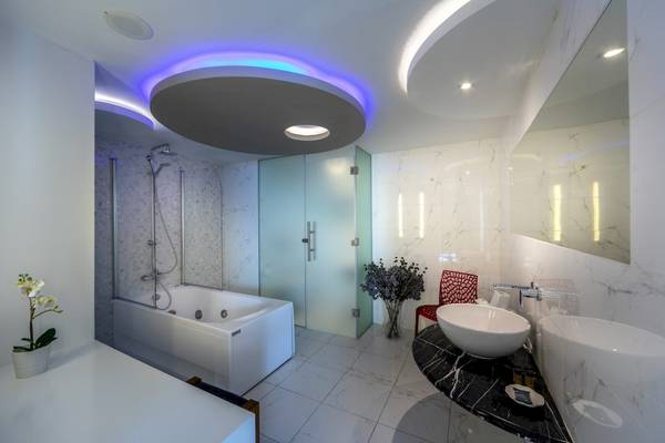 Badezimmer im Melissi Beach Hotel mit Badewanne, zwei Waschbecken und moderner Beleuchtung.