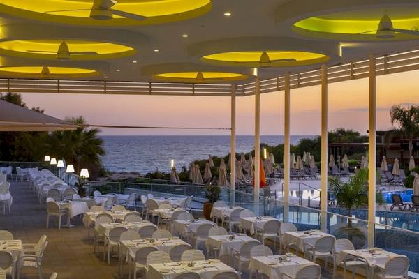 Außenrestaurant-Terrasse mit Blick auf das Meer und die Hotelanlage.