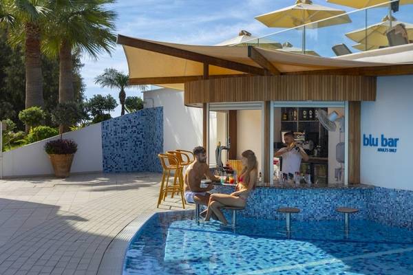 Poolbar des Melissi Beach Hotel & Spa mit einem Paar, das am Rand des Schwimmbeckens sitzt.
