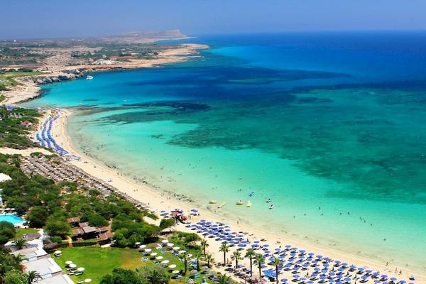 Luftaufnahme des Melissi Beach Hotel & Spa mit Strand, blauem Meer und vielen Sonnenschirmen.