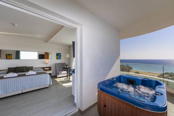 Suite im Melissi Beach Hotel mit Whirlpool und Meerblick, einschließlich eines Bettes, eines Whirlpools und eines Balkons.