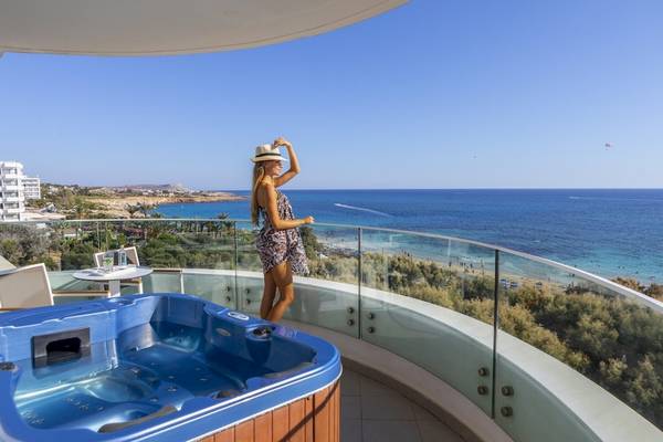 Eine Frau genießt den Ausblick auf das Meer vom Balkon des Melissi Beach Hotels mit Whirlpool.