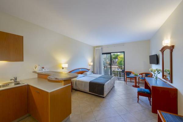 Ein modernes Hotelzimmer mit zwei Betten, einer Küchenzeile, einem Fernseher und einem Balkon.