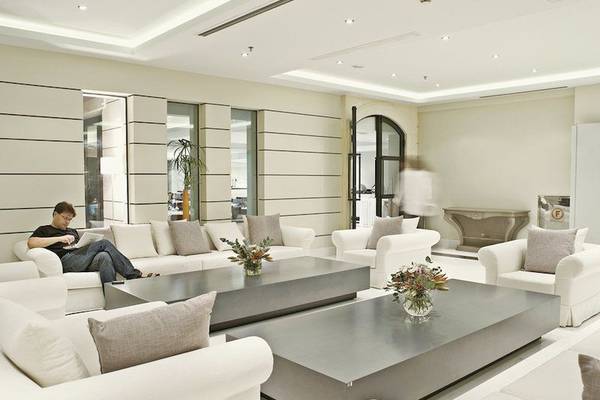 Hotellobby-Loungebereich des Aegean Pearl Hotels mit weißen Möbeln, grauen Tischen und Blumenvasen.