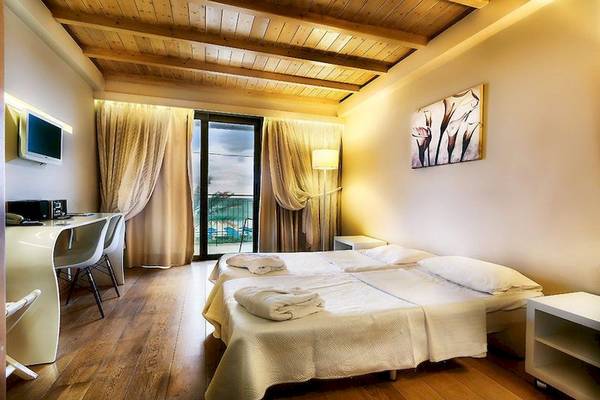Schlafzimmer des Aegean Pearl Hotels mit zwei Betten, Dekor und Aussicht durch Glastüren.