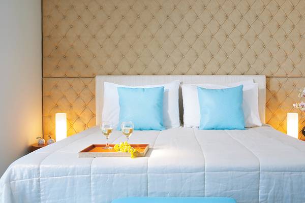 Schlafzimmer im Amirandes Grecotel Boutique Resort mit einem Bett, blauen Kissen und einer Blume.