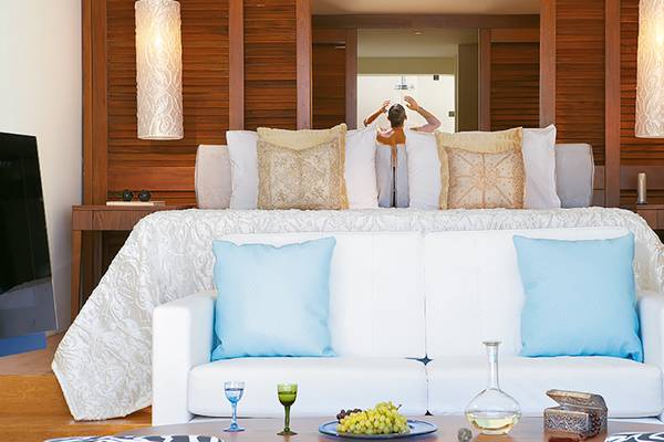 Schlafzimmer im Amirandes Grecotel Boutique Resort mit einem Bett, Kissen, Couch, Tisch und Dekor.