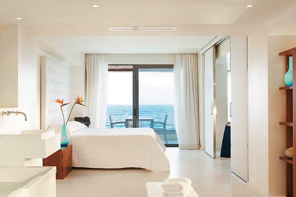 Schlafzimmer im Amirandes Grecotel Boutique Resort mit Meerblick, Bett, Balkon und Ozeansicht.