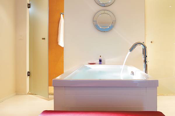Ein modernes Badezimmer mit einer Badewanne und einem Wasserhahn im Amirandes Grecotel Boutique Resort.