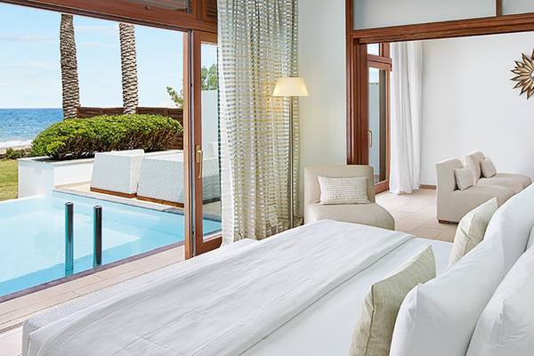Ein Blick auf eine Suite im Amirandes Grecotel Boutique Resort mit einem großen Pool und Blick auf das Meer.