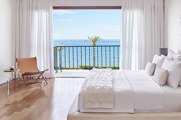 Luxuriöses Zimmer im Amirandes Grecotel Boutique Resort mit Blick auf das Meer und die Palmen.