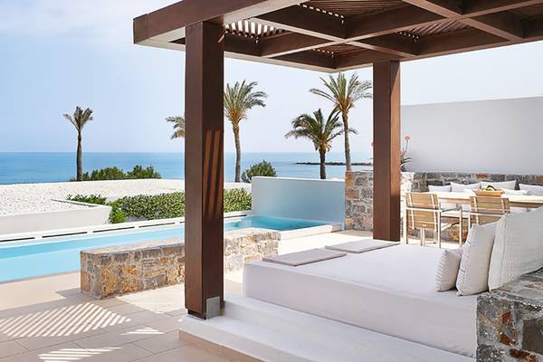 Außenbereich des Amirandes Grecotel Boutique Resorts mit Blick auf das Meer und Palmen.