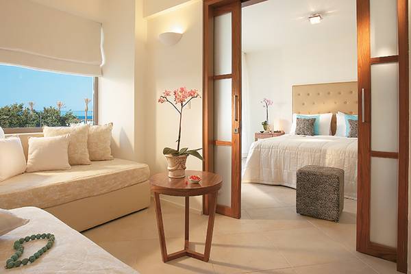 Doppelzimmer im Amirandes Grecotel Boutique Resort mit einem Bett, einem Sofa, einem Tisch mit einer Vase und einem Fernseher.