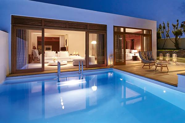 Außenbereich des Amirandes Grecotel Boutique Resorts mit Pool und Loungemöbeln bei Nacht